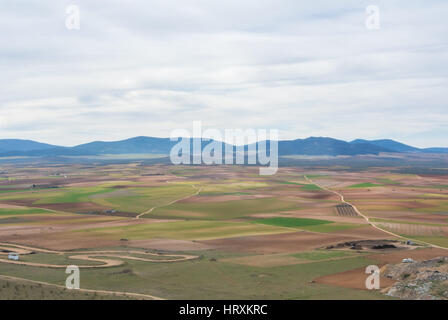 Vue d'une colline de champs, de fermes et de montagnes près de Consuegra ville au printemps jour nuageux. Banque D'Images