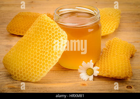 Pot en verre rempli de miel avec honeycomb sur une table en bois Banque D'Images