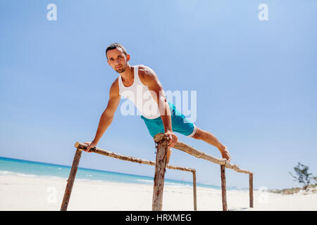 Bel homme remise en forme faire de l'exercice sur la plage avec vue sur mer Banque D'Images