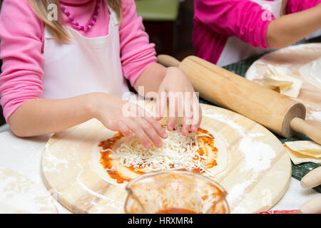 Little girl in chefs hat est une pizza cuisine Banque D'Images