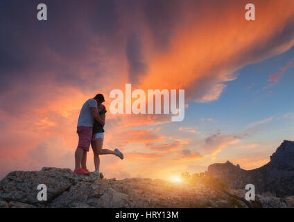 Silhouettes d'un homme embrasser et petite amie sur le sommet de la montagne au coucher du soleil. L'homme et de la femme. Paysage avec silhouette de jeunes Banque D'Images