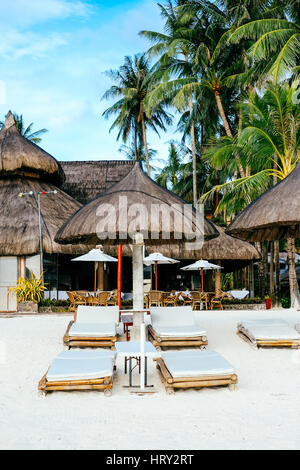 Nipa hut pare-soleil avec transats en bambou sur la plage de sable de corail blanc Banque D'Images