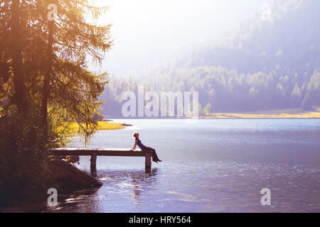 Happy woman sitting on the pier et souriant, de bonheur ou d'inspiration concept, profiter de la vie Banque D'Images