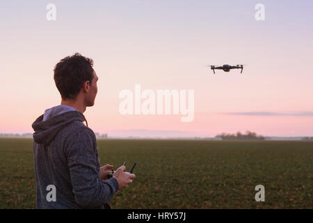 Pilotage de l'homme au coucher du soleil en plein air drone Banque D'Images