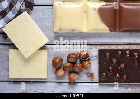 Morceaux de chocolat, tuile de noix et graines de cacao sur fond de bois Banque D'Images