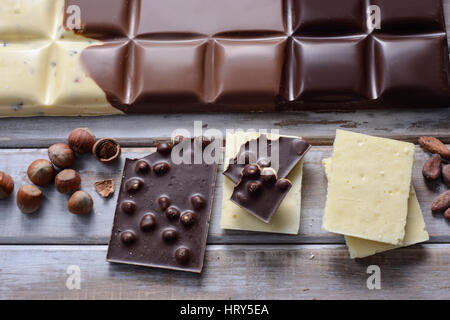 Morceaux de chocolat, tuile de noix et graines de cacao sur fond de bois Banque D'Images