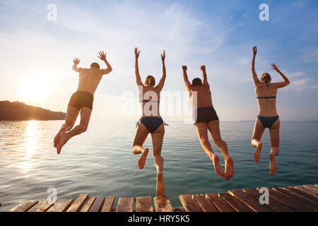 Groupe d'amis de sauter à la mer de la jetée, happy beach holidays
