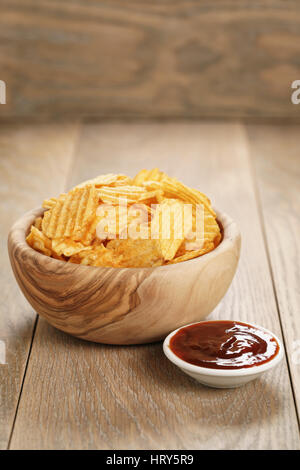 Chips de pomme de terre ridée avec le paprika et la sauce barbecue dans le bol en bois, avec copie espace Banque D'Images