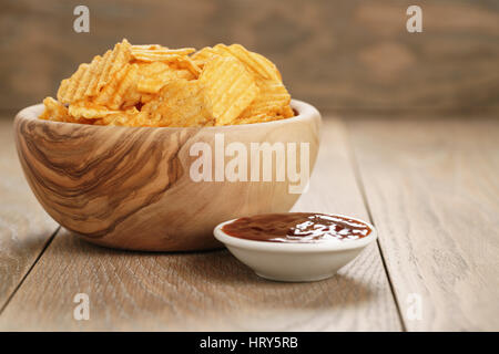 Chips de pomme de terre ridée avec le paprika et la sauce barbecue dans le bol en bois, avec copie espace Banque D'Images