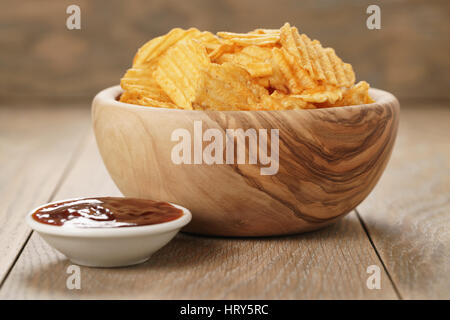 Chips de pomme de terre ridée avec le paprika et la sauce barbecue dans le bol en bois, photo gros plan Banque D'Images