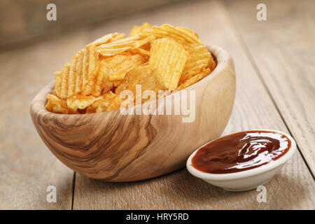 Chips de pomme de terre ridée avec le paprika et la sauce barbecue dans le bol en bois, photo gros plan Banque D'Images