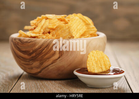 Chips de pomme de terre ridée avec le paprika et la sauce barbecue dans le bol en bois, photo gros plan Banque D'Images