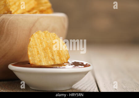 Chips de pomme de terre ridée avec le paprika et la sauce barbecue dans le bol en bois, avec copie espace Banque D'Images