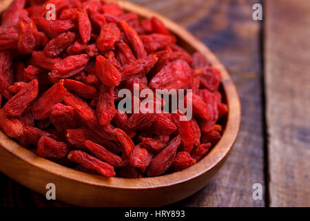 Les baies de goji dans bol en bois sur l'ancien conseil rustique,selective focus, macro Banque D'Images