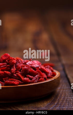 Les baies de goji dans bol en bois sur l'ancien conseil rustique,selective focus, macro Banque D'Images