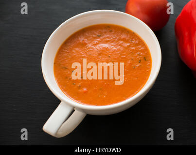 Soupe de crème aux poivrons et tomates sur la plaque noire Banque D'Images