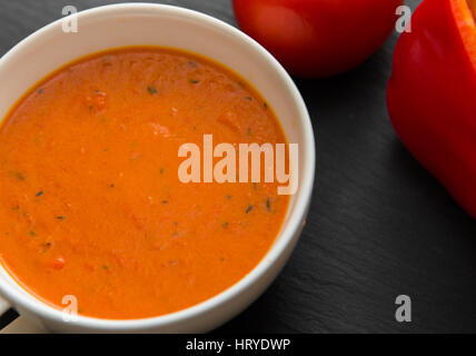 Soupe de crème aux poivrons et tomates sur la plaque noire Banque D'Images