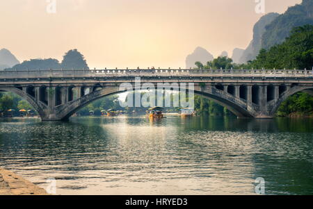 Hangzhou, Chine - 23 septembre 2016 : Bateaux de touristes qui flotte sur la rivière Li, au-dessous d'un pont de pierre, à l'heure du coucher du soleil Banque D'Images
