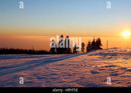 Coucher du soleil dans les montagnes enneigées et le smog dans la vallée Banque D'Images