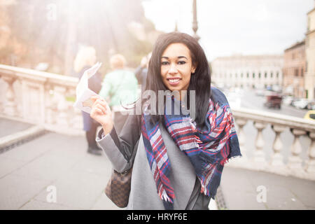 Jeune belle course mixte woman smiling and à la carte avec l'appareil photo dans la main droite, à Rome, Italie. Concept de voyage, de vie moderne, conte Banque D'Images