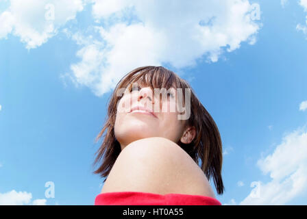 Junge Frau unter blauem Wolkenhimmel - jeune femme en bleu, ciel nuageux Banque D'Images