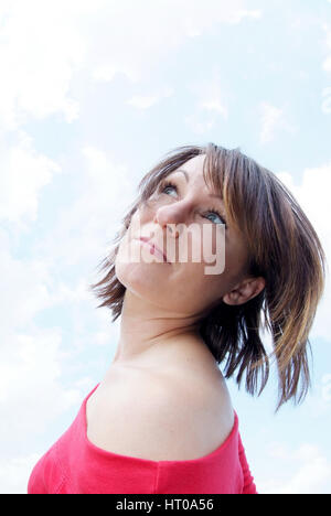 Junge Frau unter Wolkenhimmel - jeune femme en bleu, ciel nuageux Banque D'Images