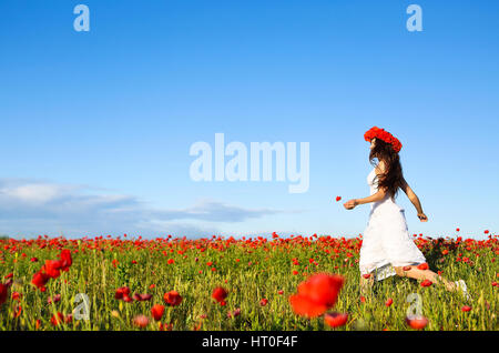 Les jeunes bonne course femme dans champ de coquelicots Banque D'Images