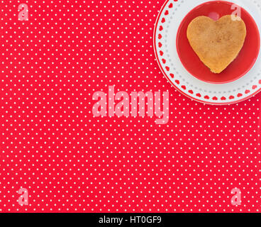 Heart-Shaped crêpe sur une plaque rouge avec fond Textile en pointillés rouges Banque D'Images