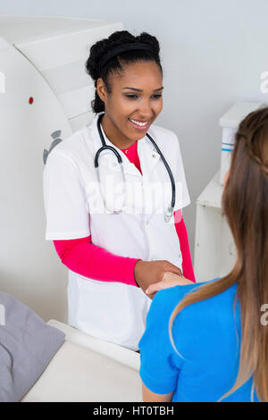 Smiling female doctor shaking hand with patient assis machine ct scan à l'hôpital Banque D'Images