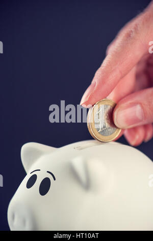 Woman putting un euro coins in piggy bank, d'épargne et de l'argent accueil concept budgétaire Banque D'Images