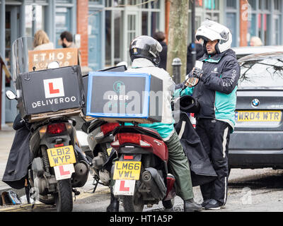 Deliveroo et Uber mange chat riders livraison en attendant pour les commandes près de London's Spitalfields Market Banque D'Images