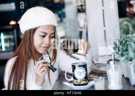 Belle jeune fille portant des vêtements blancs plateau driniking dans un bar Banque D'Images