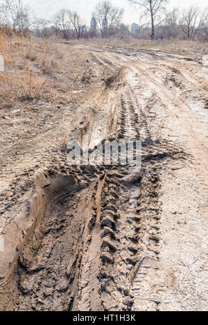 Des morceaux de pneus sur la route couverte par sable boueux humide Banque D'Images
