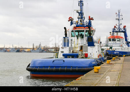 Swinoujscie, Pologne - 21 Février 2017 : Deux remorqueurs dans le port sont amarrés sur le quai - en attente d'utilisation. Dans l'arrière-plan sont plusieurs navires de guerre. Banque D'Images