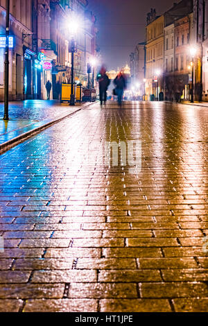 Nuit dans la rue, Pologne. L'éclairage de nuit en raison de la chaussée de pierre humide de la vieille ville. Belle photo de fond. Banque D'Images