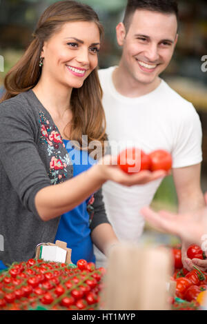 Couple qui achète des légumes biologiques frais at market Banque D'Images