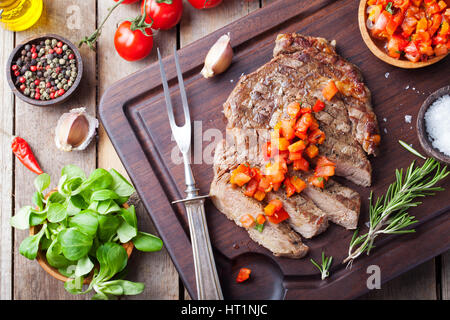 Pavé de boeuf bien fait avec de la tomate et du poivre salsa on a wooden background Banque D'Images