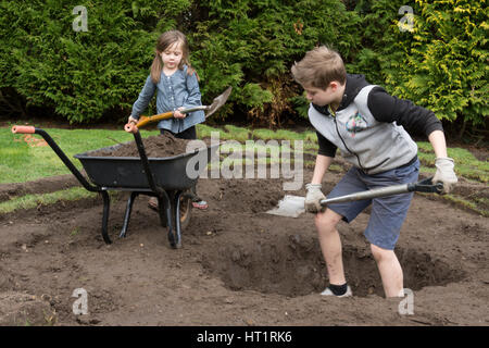 Jeune fille et garçon creuser l'étang de la faune dans le jardin Banque D'Images