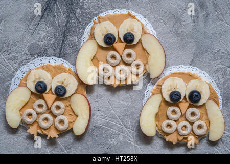Funny owl avec du beurre d'arachide, de céréales et de fruits pomme banane sur gâteau de riz pour les enfants Petit déjeuner Banque D'Images