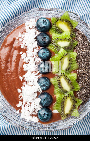 Boisson fouettée aux petits déjeuner bol garni de bleuets, kiwi, graines de chia, flocons de noix de coco pour petit-déjeuner sain, selective focus Banque D'Images