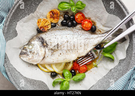 Les poissons la Bram, cuit dans une casserole avec les légumes et le citron, olives noires. Le basilic frais . Dîner santé Banque D'Images