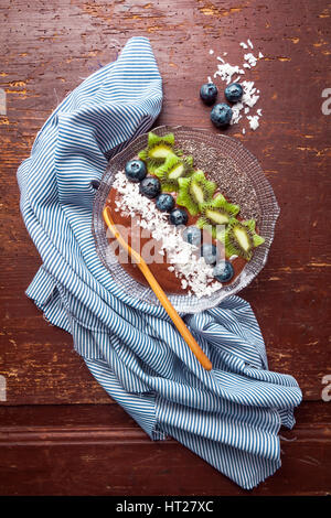 Boisson fouettée aux petits déjeuner bol garni de bleuets, kiwi, graines de chia, flocons de noix de coco pour petit-déjeuner sain, selective focus Banque D'Images