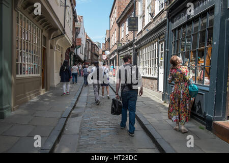 Consommateurs et aux touristes anglais profitez d'une journée d'été sur Low Petergate, York, North Yorkshire, UK. Banque D'Images