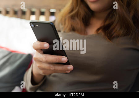 Close-up femme textos message sur téléphone dans café shop Banque D'Images