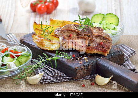 Repas grec : Poêlée de côtelettes d'agneau au four avec les quartiers de pommes de terre, les agriculteurs de la salade et sauce tzatziki Banque D'Images