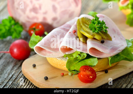 Rouleaux d'une tranche de jambon et des cornichons saucisse servie sur une planche en bois rustique Banque D'Images