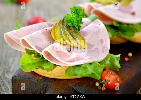 Rouleaux d'une tranche de jambon et des cornichons saucisse servie sur une planche en bois rustique Banque D'Images