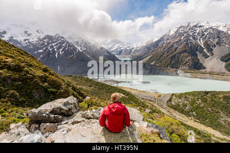 Randonneur assis sur des rochers, vue dans la vallée de Hooker Sealy Tarns Track, lacs glaciaires Mueller et le lac Hooker Lake Banque D'Images