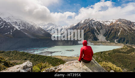 Randonneur assis sur des rochers, vue dans la vallée de Hooker Sealy Tarns Track, lacs glaciaires Mueller et le lac Hooker Lake Banque D'Images