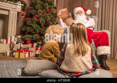 Père Noël avec enfants lecture d'envies Banque D'Images